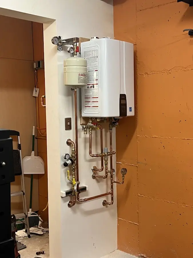 Plumbing technician inspecting water heater connections in Golden